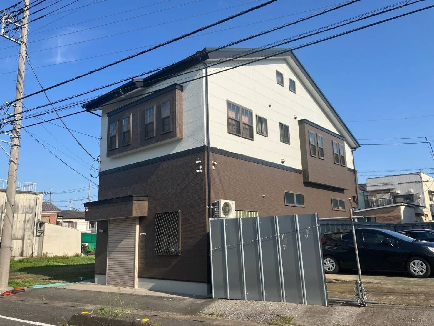 川口市のモダンなツートンカラー（ブラウン×ホワイト）の3階建て住宅。外壁塗装やリフォームの施工事例として、外観デザイン、窓の配置、周辺環境を捉えた写真。