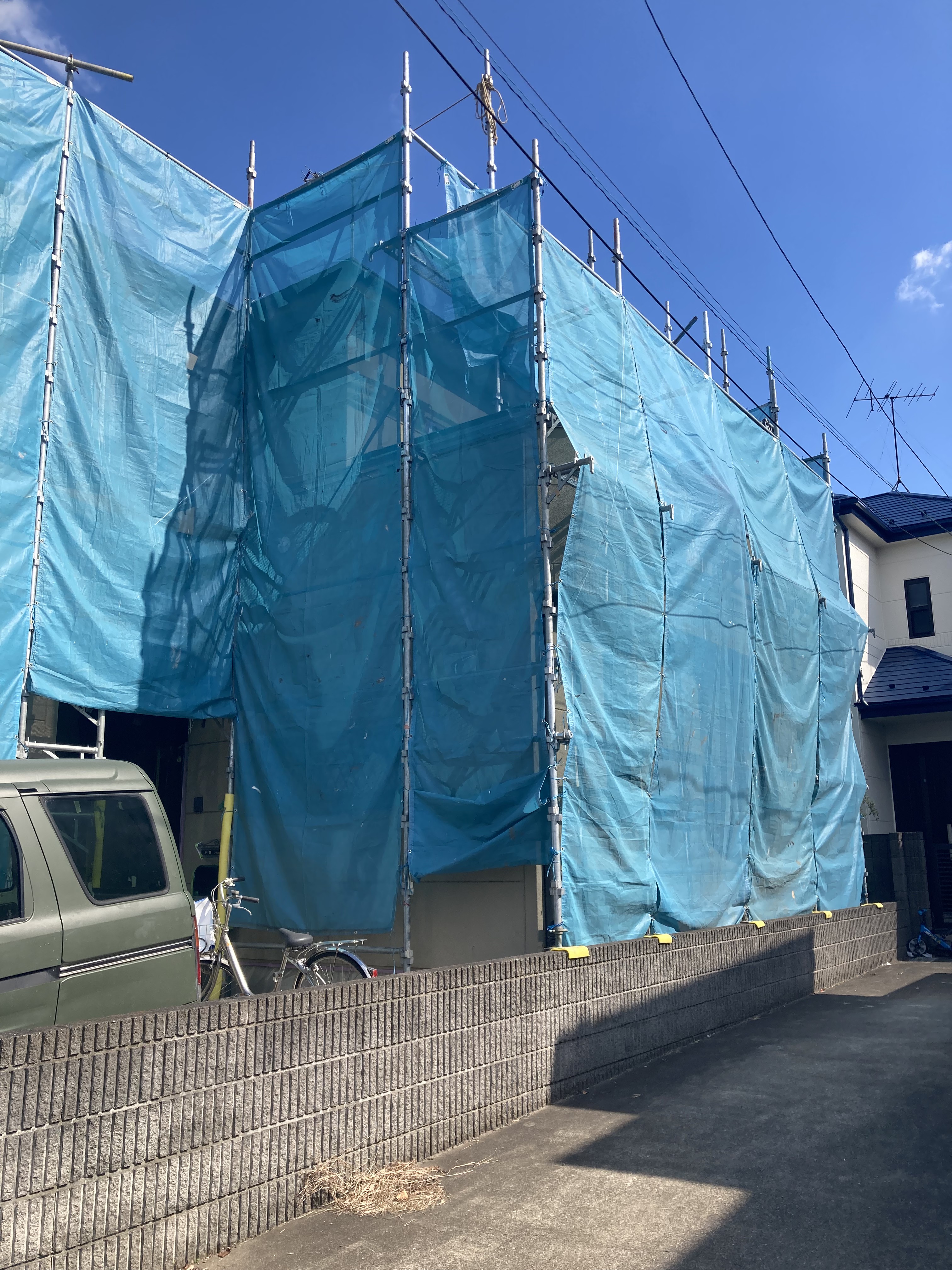 三郷市で安全に作業を行うために住宅全体に設置された飛散防止ネット付きの足場