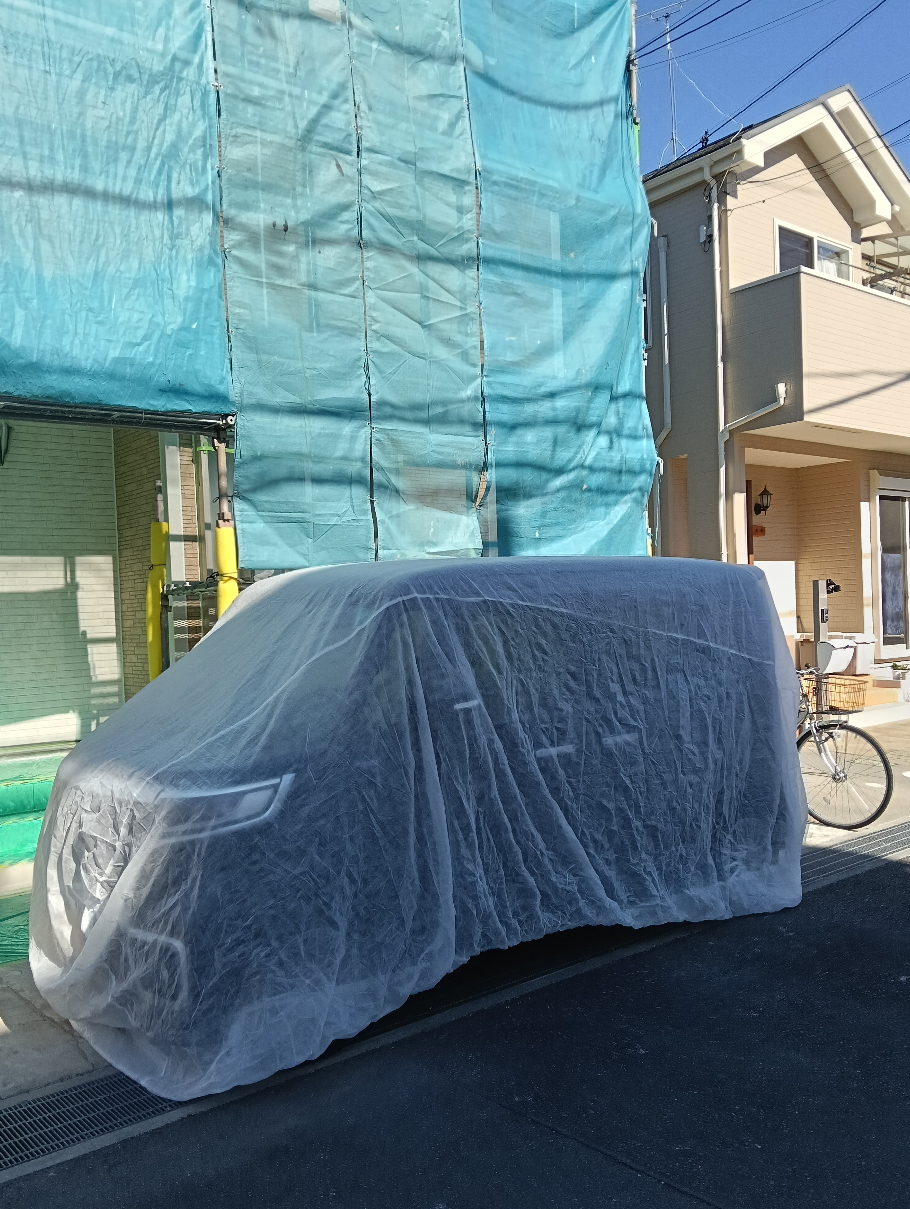 近隣への配慮を徹底。川口市の現場にて、塗装の飛散から大切なお車を守るため、専用の自動車保護カバー（カーシート）で丁寧に養生します。