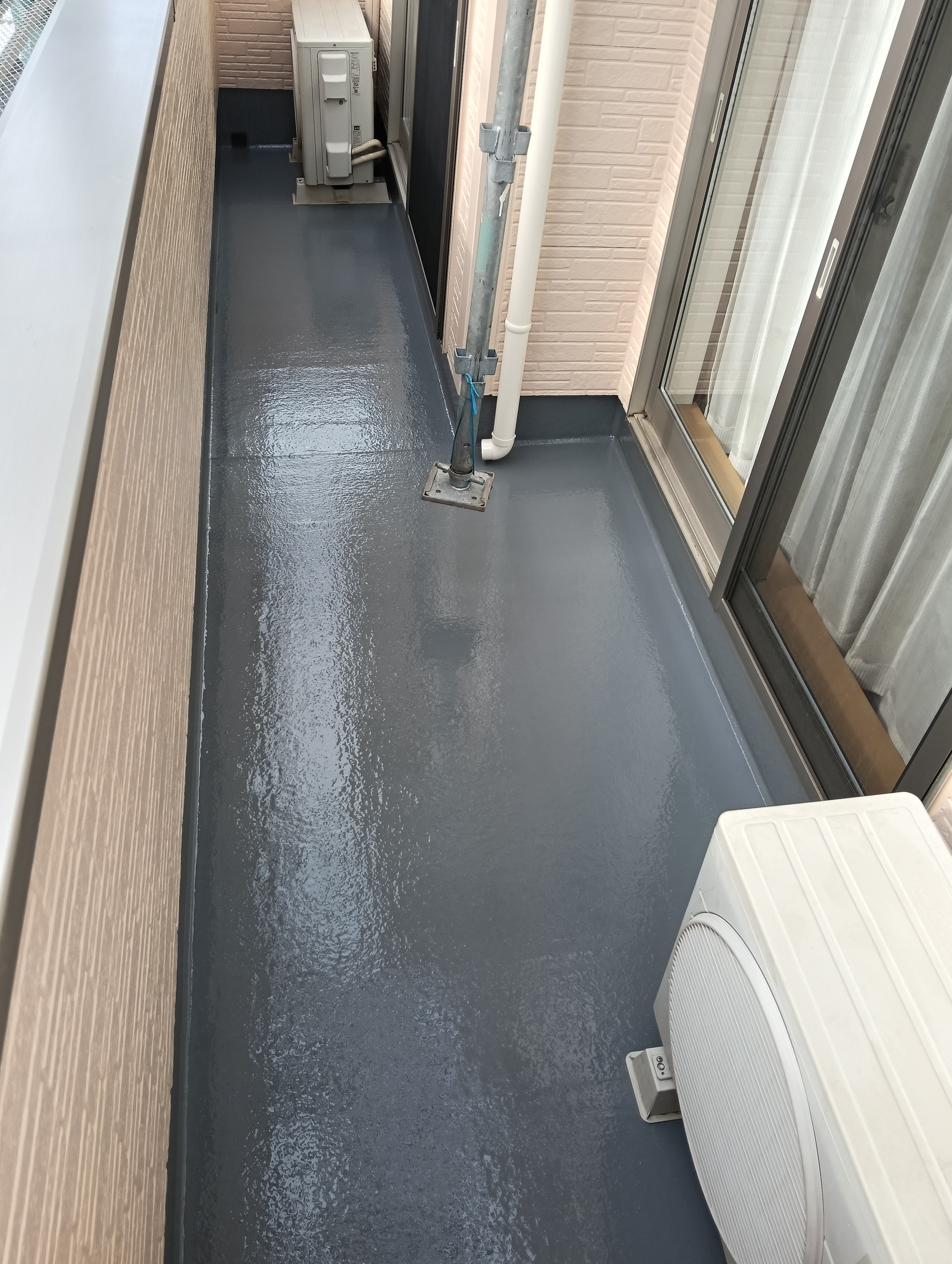 川口市でのベランダ防水メンテナンス。既存の防水層を保護し、雨水の侵入を防ぐためのトップコート塗布による表面仕上げ。
