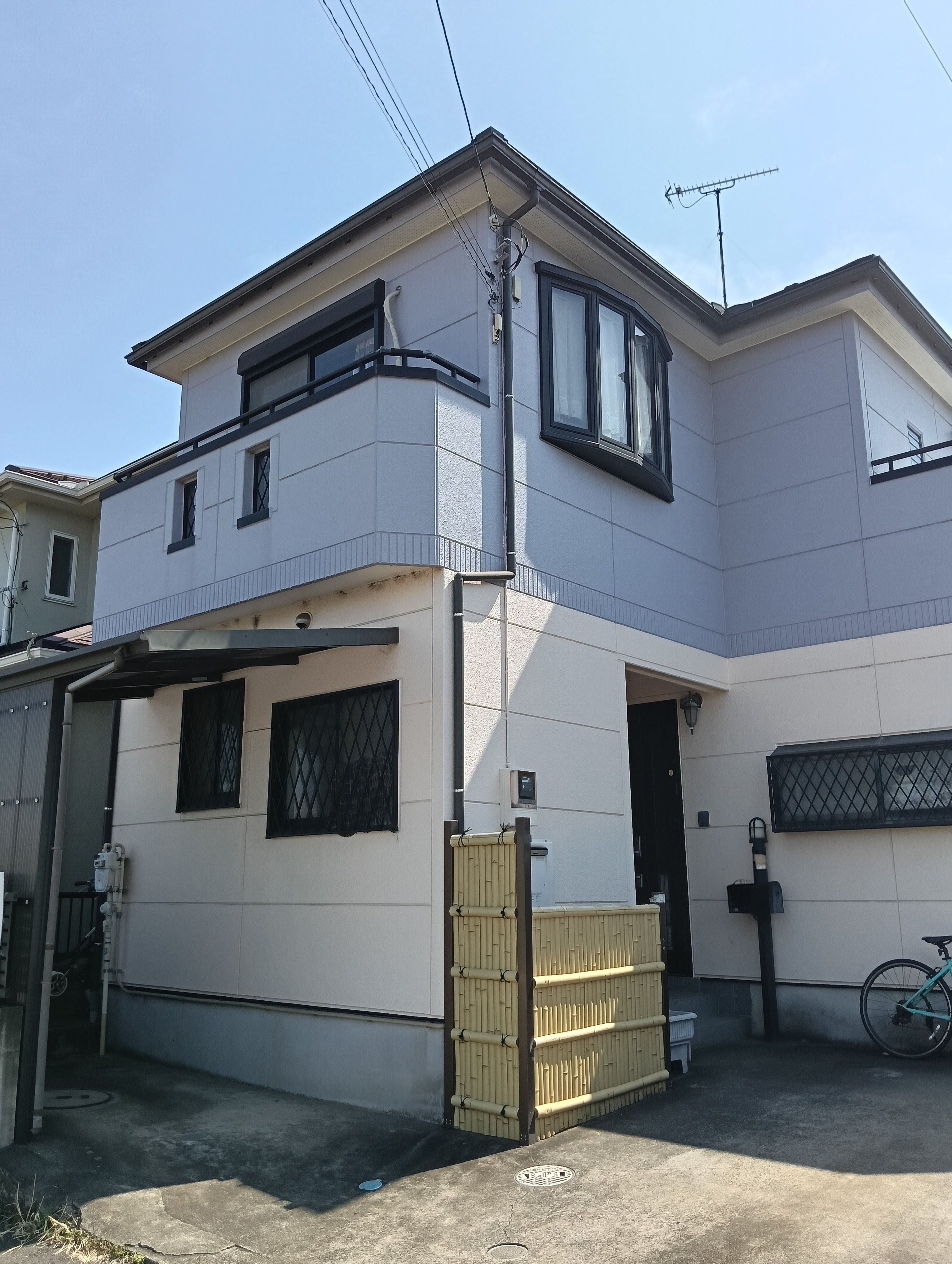 グレーとホワイトのツートンカラーで塗り替えられた、モダンな印象の2階建て住宅の施工後写真