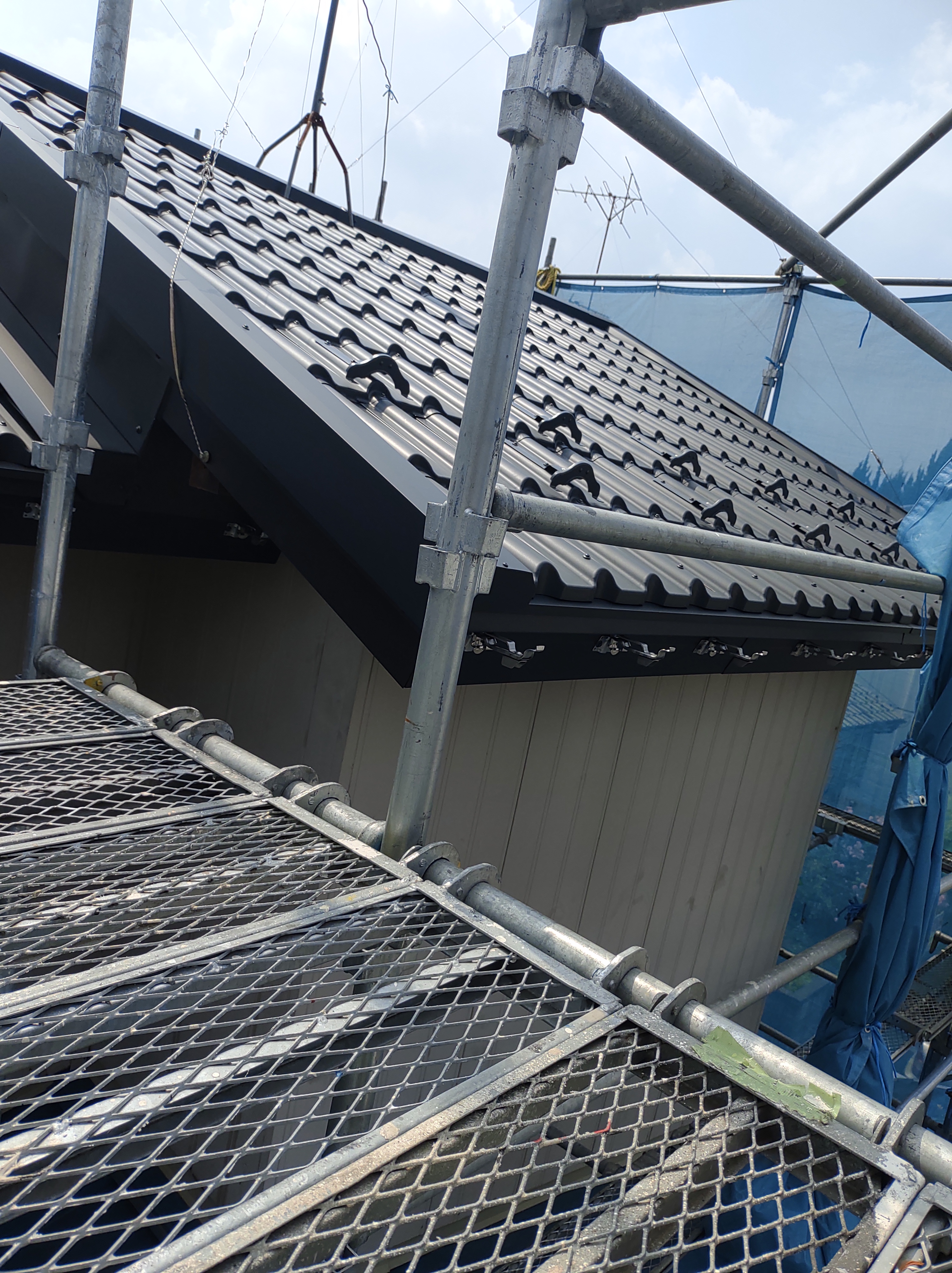 川口市での屋根リフォーム施工中の様子。敷設した防水ルーフィングの上から、耐久性の高い新しい金属屋根材(ガルバリウム鋼板)を丁寧に葺いていく設置工程。