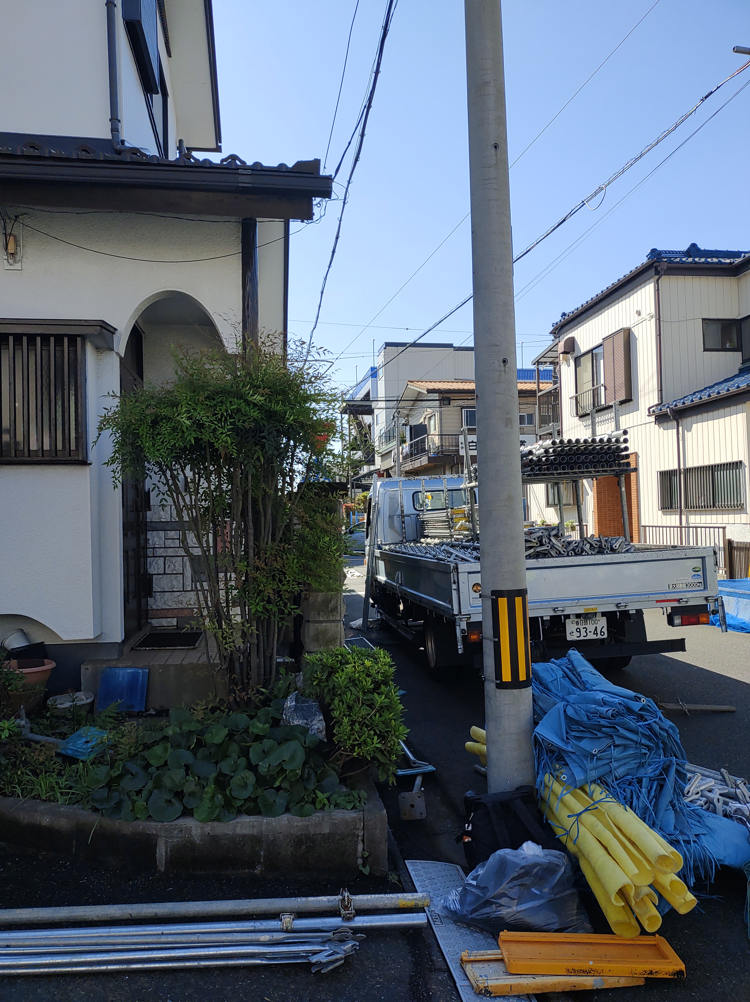塗装工事が完了し、美しい艶と細かな凹凸模様が均一に仕上がった白いモルタル外壁。足場から建物の側面を見通したアングル。