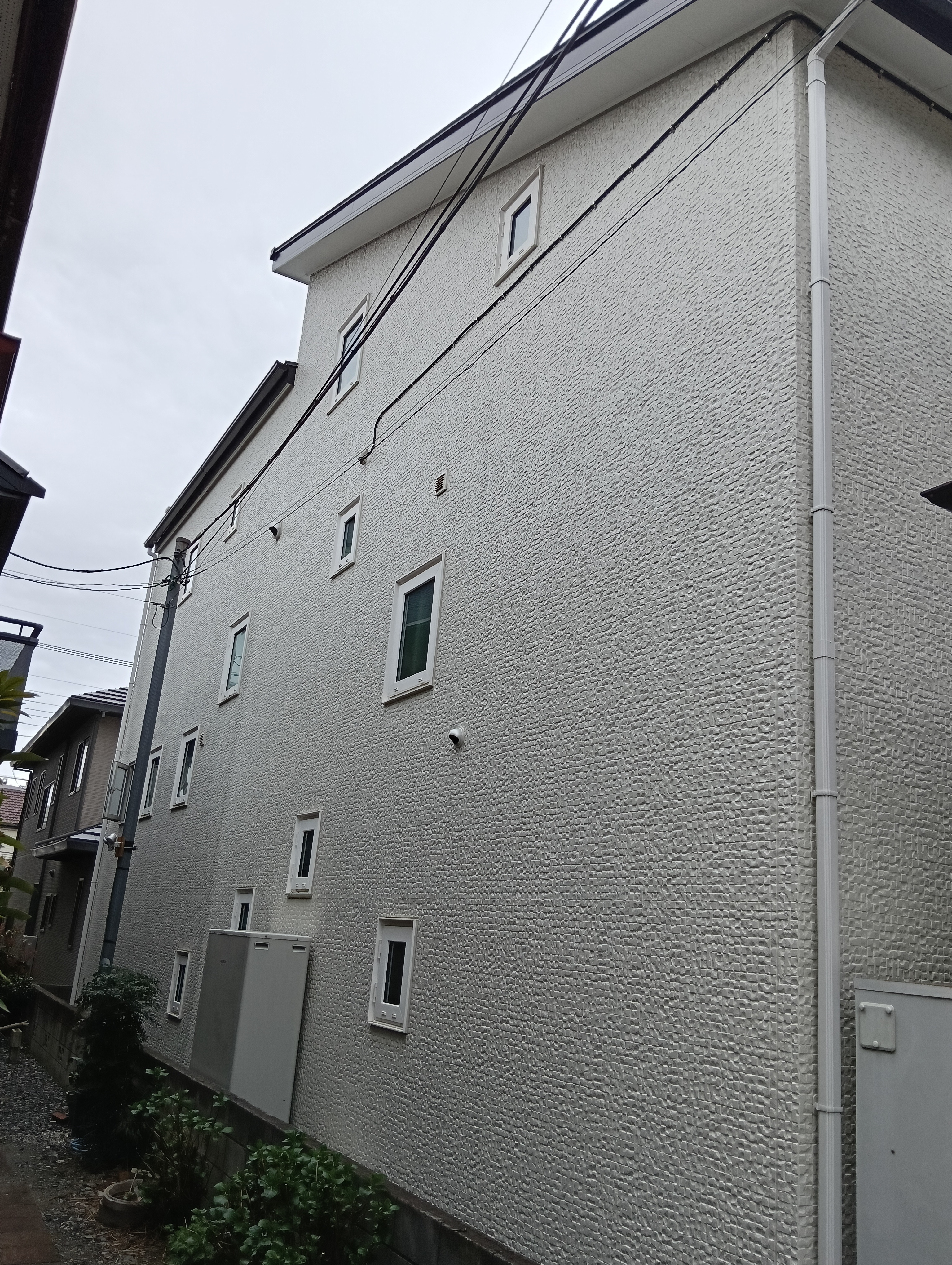川口市での外壁塗装・屋根リフォーム施工事例。モダンな白外壁の雨だれ・黒ずみ汚れのお悩みを、セルフクリーニング機能を持つ低汚染塗料で解決!グレーのアクセント壁を引き締め、新築時の美しい輝きを再現しました。