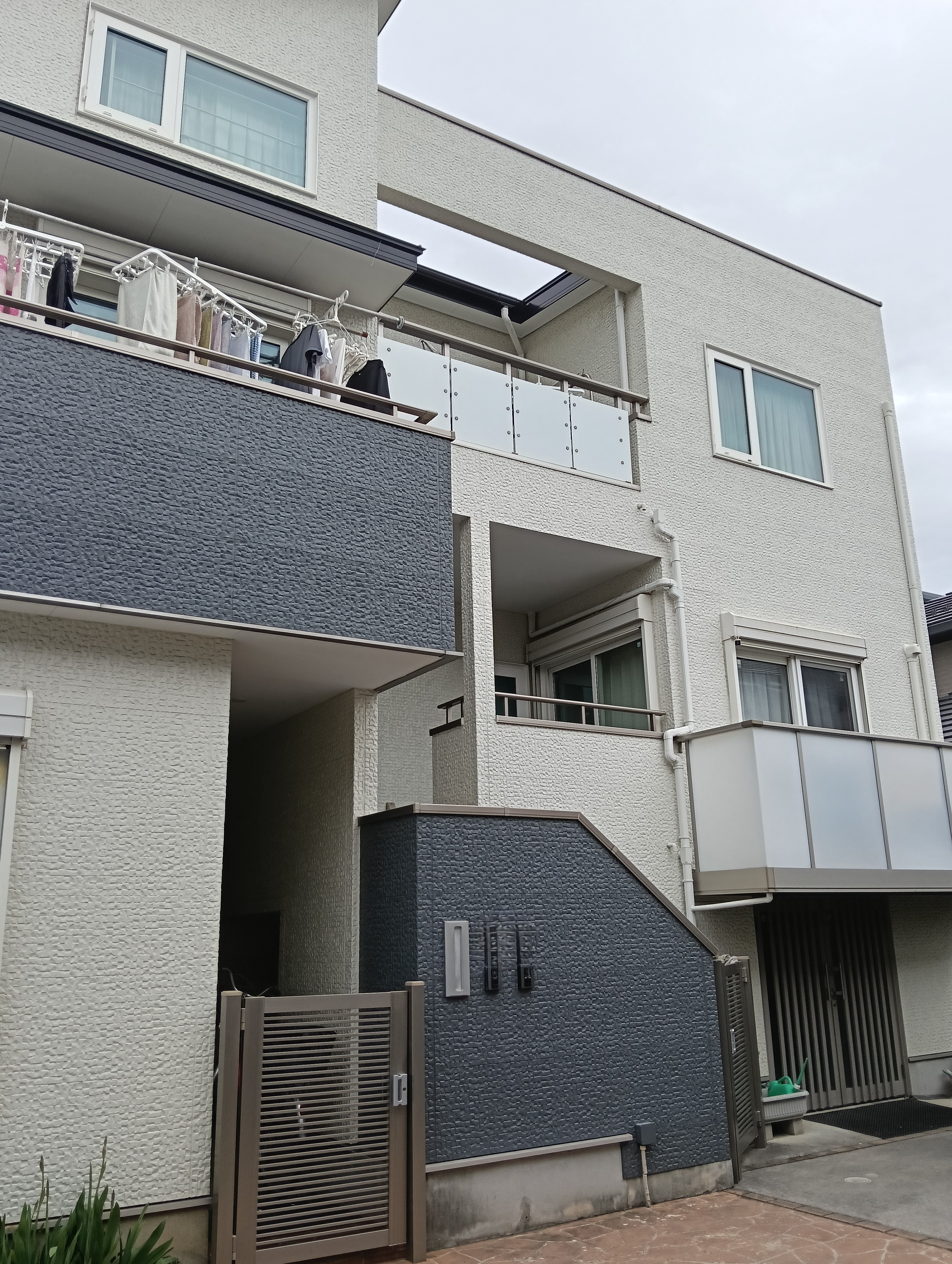 川口市での外壁塗装・屋根リフォーム施工事例。モダンな白外壁の雨だれ・黒ずみ汚れのお悩みを、セルフクリーニング機能を持つ低汚染塗料で解決!グレーのアクセント壁を引き締め、新築時の美しい輝きを再現しました。