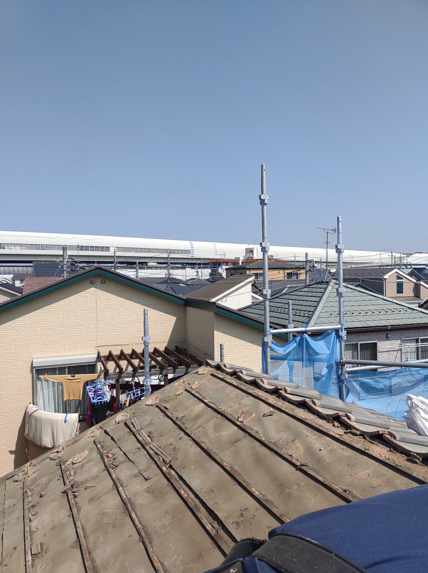 草加市の戸建て屋根葺き替えリフォーム現場にて、古い日本瓦をすべて撤去・ハツリ処分し、雨漏り点検と補強を行うために木の下地野地板を完全に露出させた工事中の写真