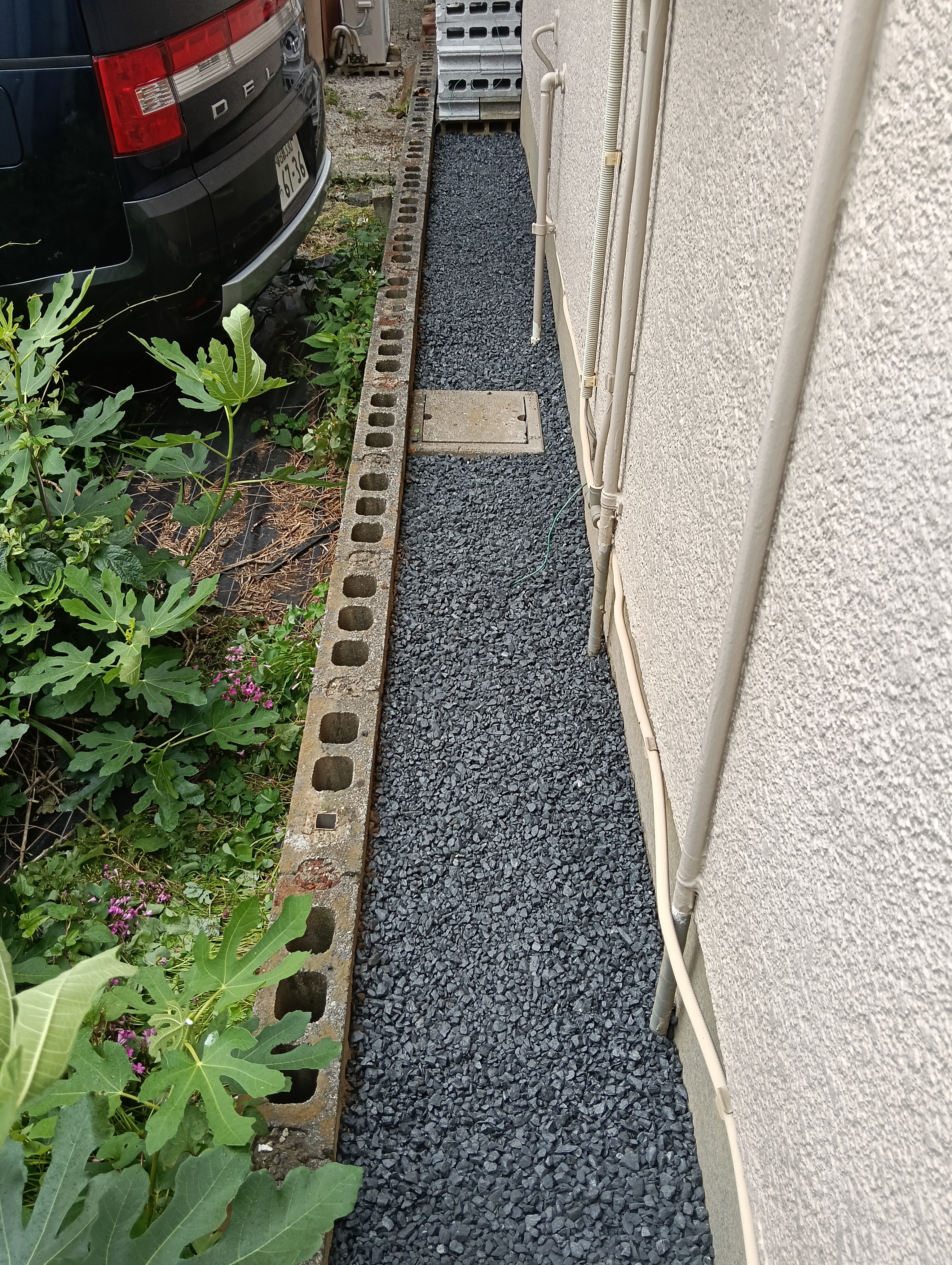 草加市の外構フェンス入替工事にて、防草シートの上にグレーの砂利を均一な厚みで美しく敷き詰めた犬走り通路の施工中写真