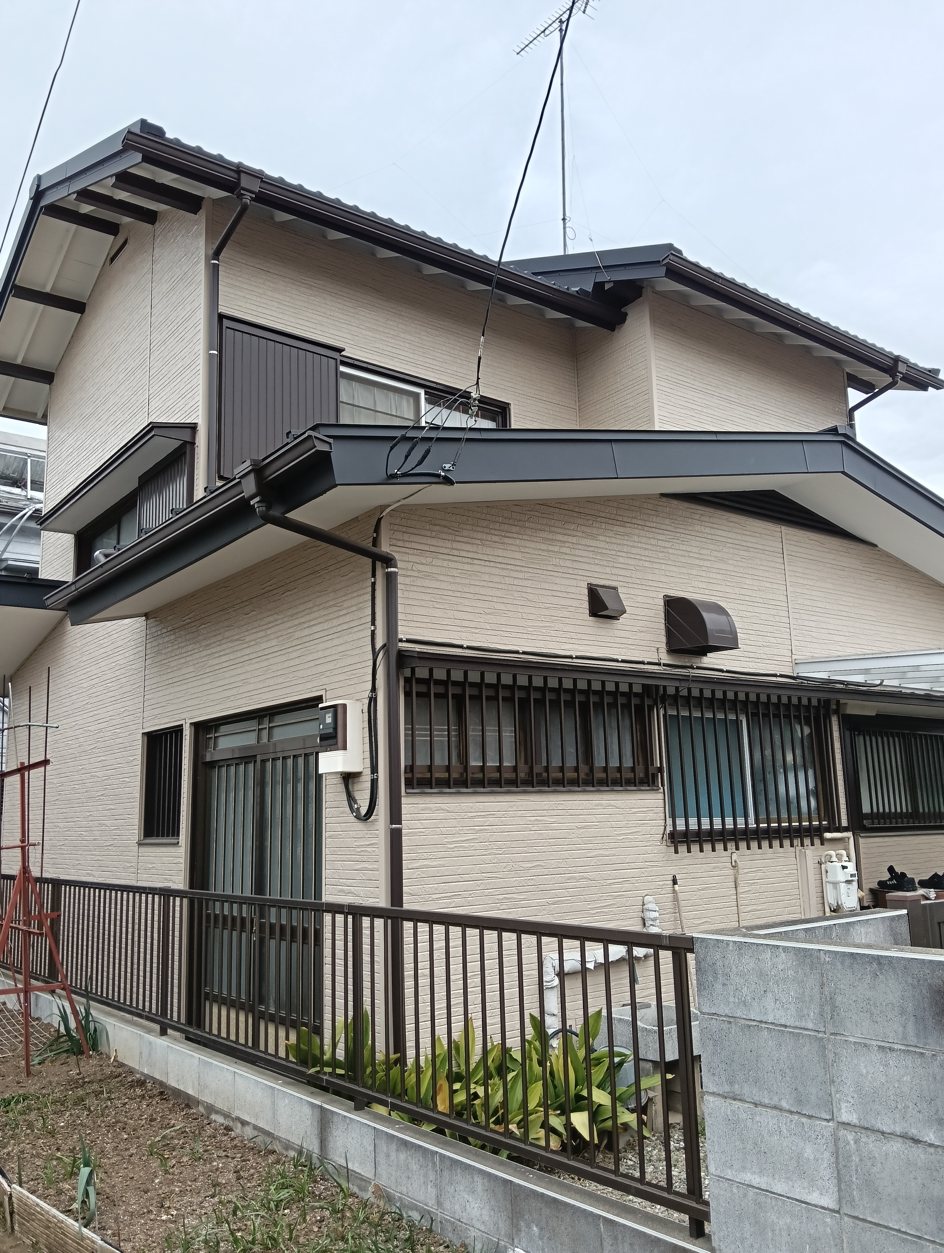 川口市での住宅リフォーム施工事例。外壁の金属サイディング張替え工事と、屋根の葺き替え工事が完了した和モダンな2階建ての住宅外観。